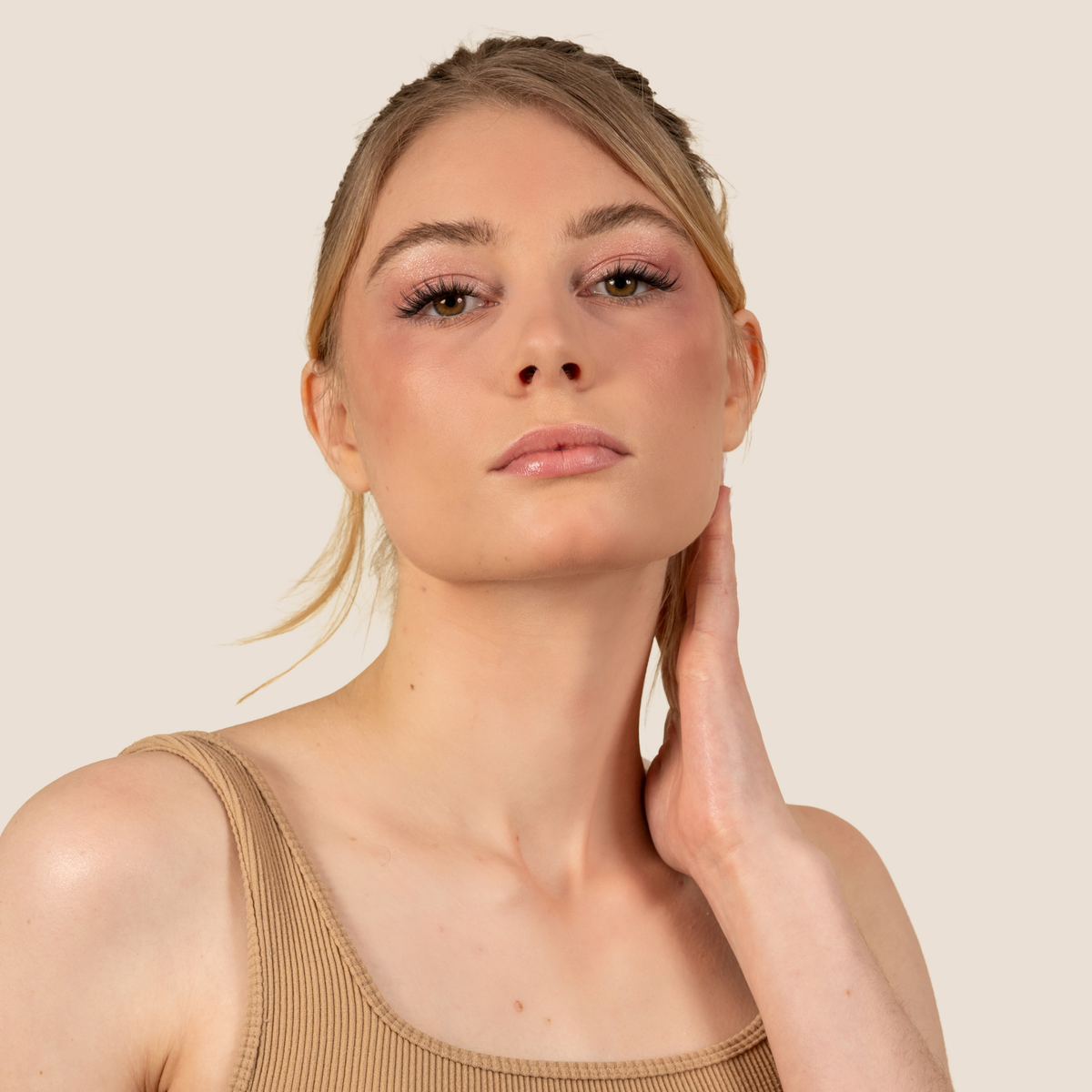 Femme blonde main sur le cou, regard mis en valeur par des faux cils légers