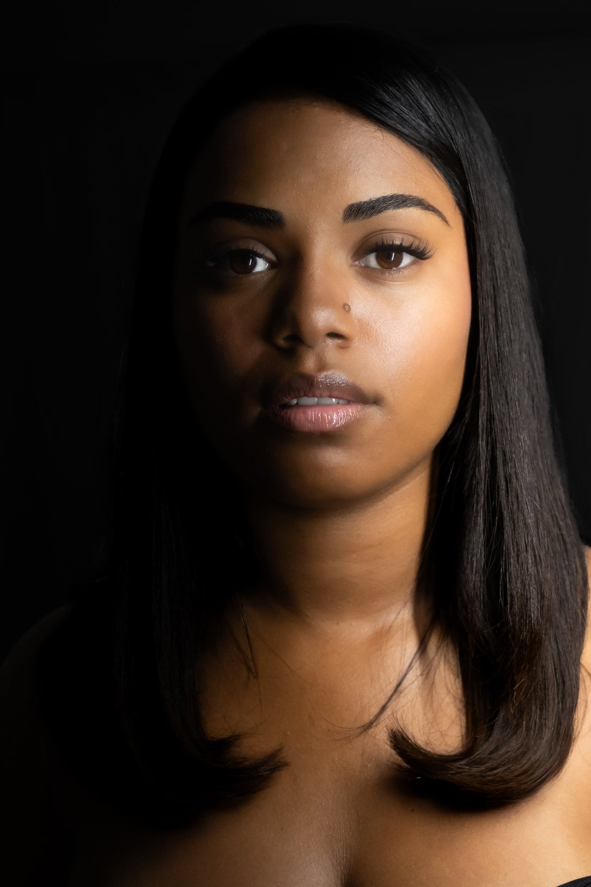 Portrait sur fond noir d'une femme portant les cils press-on GLAMOUR