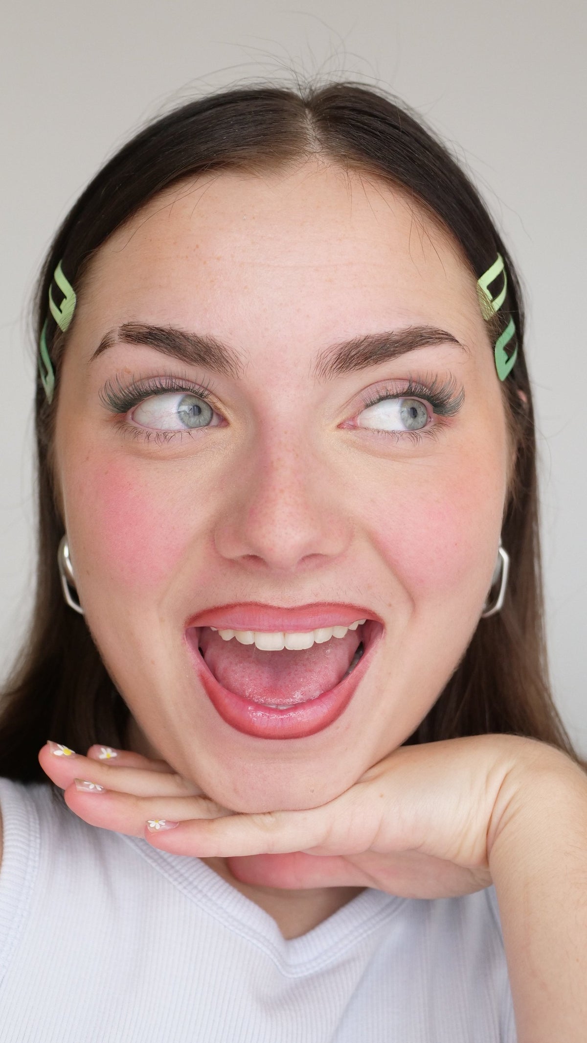 Jeune femme expressive aux barrettes colorées portant des faux cils de couleur