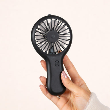 Main tenant le mini ventilateur portable noir sur fond blanc